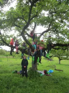 Gesine Langlotz steht vor einem großen Obstbaum, auf dem viele Kinder sitzen.